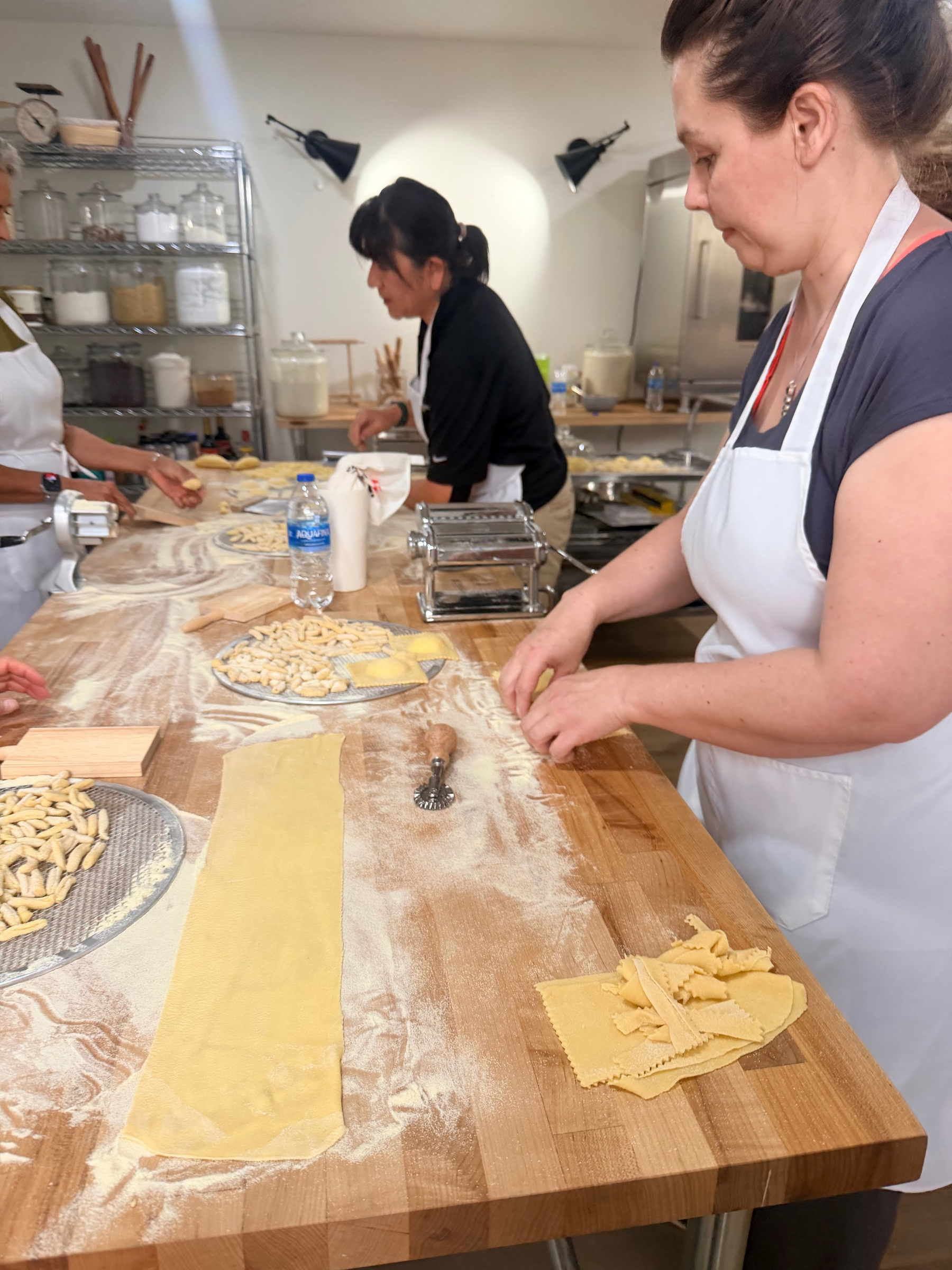 Friends making fresh pasta during a private cooking class at Eat Well ABQ in Albuquerque