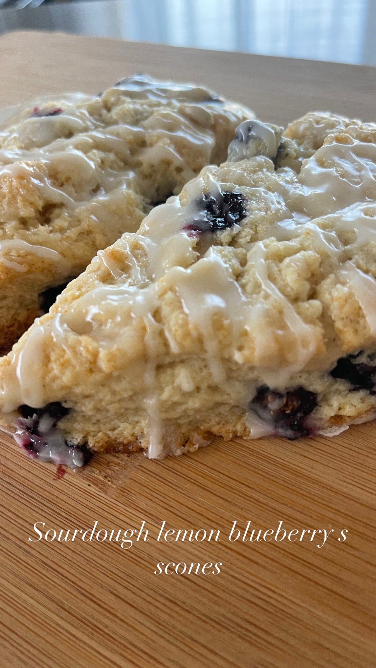 Sourdough lemon blueberry scones with glaze on a wooden surface.